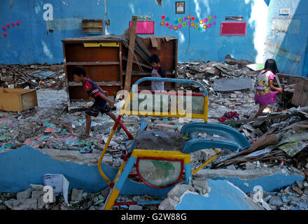 Gresik, Indonesia. Il 3 giugno, 2016. I bambini raccogliere libri e attrezzature tra le rovine del Kusuma Asilo nido a Gresik, East Java, Indonesia, 3 giugno 2016. L'edificio è crollato dopo le tempeste e le forti piogge hanno colpito Gresik giovedì. © Kurniawan/Xinhua/Alamy Live News Foto Stock