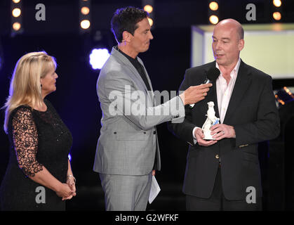 Monaco di Baviera, Germania. 03 Giugno, 2016. Produttori Gerda Mueller (L) e Jan Kromschroeder (R) sono presentati con il "Blue Panther' per 'Club der Roten Baender' (lit. Club delle strisce rosse) dal presentatore televisivo Sebastian Hellmann (C) durante la Televisione Bavarese cerimonia di premiazione si terrà a Monaco di Baviera, Germania, 03 giugno 2016. La Televisione Bavarese Award è stato presentato dal 1989. Foto: TOBIAS HASE/dpa/Alamy Live News Foto Stock