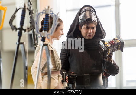 Hannover, Germania. 04 Giugno, 2016. Una donna e un uomo vestito da Rey (L) e Kylo Ren dal film Star Wars franchise guardare un puntello versione di Thor del martello dal Marvel franchising presso lo stand di Fabion presso il fumetto di MCM Con ad Hannover, Germania, 04 giugno 2016. Gli espositori, stelle e le ventole si riuniranno per l'evento che si terrà dal 04 al 05 giugno 2016. Foto: SEBASTIAN GOLLNOW/dpa/Alamy Live News Foto Stock