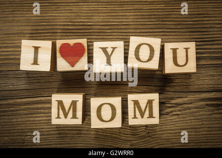 Messaggio ti amo mamma fatta di lettere su blocchi di legno. La festa della mamma. Lettere e forma di cuore disegnato dall'autore in una scheda grafica Foto Stock
