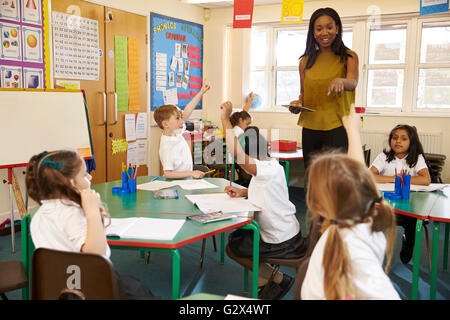 Insegnante con tavoletta digitale nella scuola elementare Classroom Foto Stock