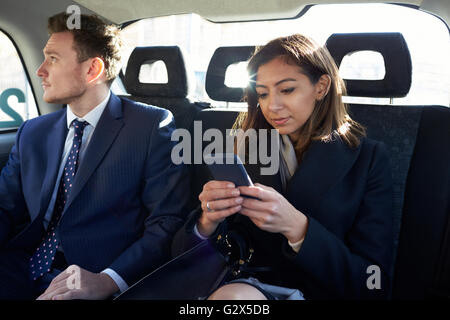 Gli imprenditori che viaggiano in Taxi utilizzando i telefoni cellulari Foto Stock