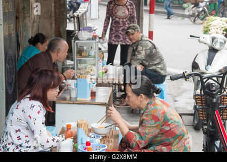 Gente locale vietnamita che fa colazione in uno Street Cafe nel quartiere vecchio di Hanoi, Vietnam, Asia Foto Stock