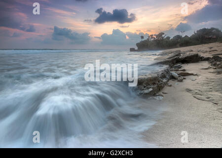 Schizzi d'onda sul naturale di roccia costiere durante il tramonto da favola. Foto Stock