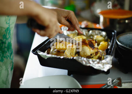 Donna tagliare un pollo arrosto Foto Stock