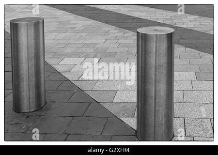 Foto in bianco e nero di un acciaio inossidabile bollard sul marciapiede grigio con poche righe di colore grigio scuro di lastre per pavimentazione con un vintage bo Foto Stock