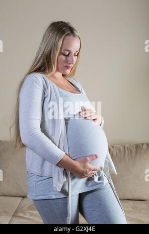 Donna incinta di accarezzare il suo ventre Foto Stock