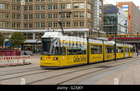 Un tram giallo M4 Berlin fa sì che si attraversi Alexanderplatz, una grande piazza pubblica nel quartiere Mitte di Berlino, Germania Foto Stock