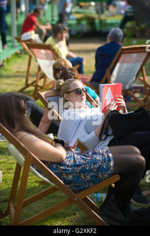 Giovani donne la lettura di libri sat in sedie a sdraio a Hay Festival 2016 Foto Stock