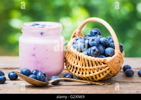 Mirtilli freschi yogurt nel vaso e piccolo cestino di mirtilli. Foto Stock