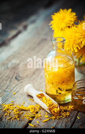 Bottiglia di tarassaco tintura o olio, mazzo di fiori e di miele sul tavolo. la medicina di erbe. Foto Stock