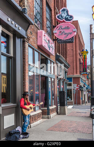 Country Music street performer a suonare la chitarra e cantare accanto a Bettie Page negozio di abbigliamento a Broadway nel centro di Nashville Foto Stock