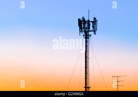 Silhouette della torre cellulare contro blu, rosa e arancione tramonto Cielo. Noto anche come sito di cella o cella tower è dove le antenne di un Foto Stock