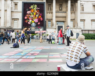 Marciapiede artista in Trafalgar Square, London, Regno Unito - colorata gesso disegni di bandiere nazionali Foto Stock