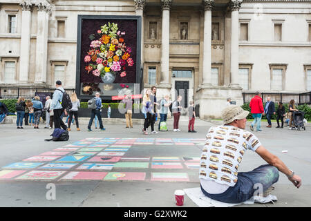Marciapiede artista in Trafalgar Square, London, Regno Unito - colorata gesso disegni di bandiere nazionali Foto Stock