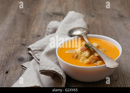 Zuppa di zucca - purea con crostoni di pane in una ciotola bianco sul vecchio sfondo di legno Foto Stock