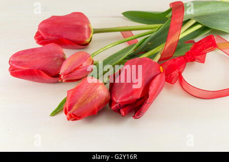 Tulipani rosso su bianco tavola di legno Foto Stock