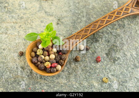 Pepe grani spezie in un cucchiaio di legno su un tavolo di pietra Foto Stock