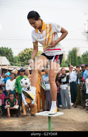Una donna di giocoleria con una piccola sfera di calcio e gli anelli sulla sommità di una piccola piattaforma, demoso, Stato Kayah, myanmar Foto Stock