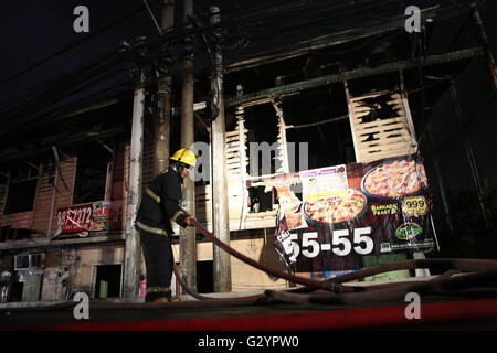 Manila, Filippine. 5 Giugno, 2016. Un vigile del fuoco tira un tubo flessibile di acqua dopo un incendio in una zona residenziale a Manila nelle Filippine, Giugno 5, 2016. Circa 100 famiglie hanno perso le loro case nel fuoco, secondo il Philippine Bureau of Fire. © Rouelle Umali/Xinhua/Alamy Live News Foto Stock