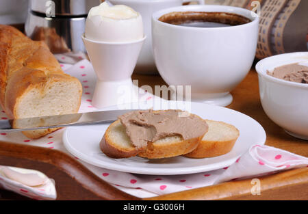 Una fetta di pane tostato spalmato con patè di fegato per la prima colazione e una tazza di caffè su un vassoio Foto Stock