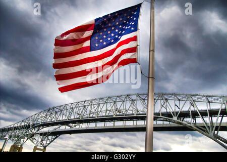 Bandiera americana. Bandiera americana con il Blue Water Bridge international border crossing come sfondo. Questo è il confine. Foto Stock