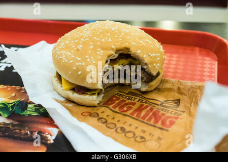 Hamburger con un morso preso fuori di esso, su un vassoio in un Burger King e un ristorante fast-food. Foto Stock