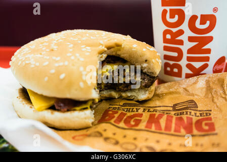 Hamburger con un morso preso fuori di esso, e bere su un vassoio in un Burger King e un ristorante fast-food. Foto Stock