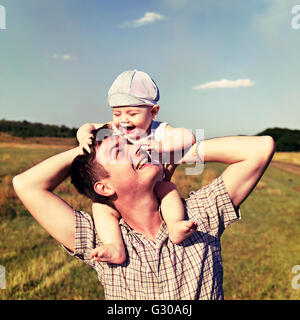 Padre contiene un piccolo bambino sulle sue spalle Foto Stock