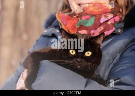 La donna mantiene il gatto nero sulle mani Foto Stock