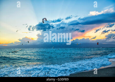 Bocale, Reggio Calabria beach. Ragazzi vanno kite surf al tramonto con colori nuvole. Questo sport è molto praticato in questa zona. Foto Stock