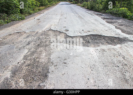 Strada danneggiata in campagna, danneggiato asfalto con buche causate, cattiva strada. Foto Stock