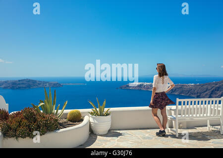 Giovane donna sorge nei pressi del banco e guardando il mare Foto Stock