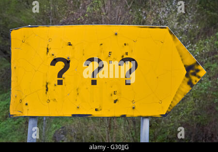 Tre punti di domanda scritta su un giallo cartello stradale Foto Stock