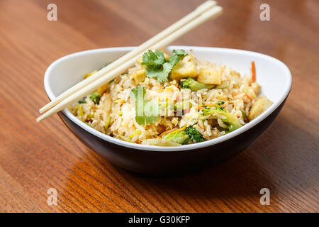 Asian riсe con tofu e verdure nella targhetta ovale con canne di bambù su un tavolo di legno nel ristorante asiatico Foto Stock