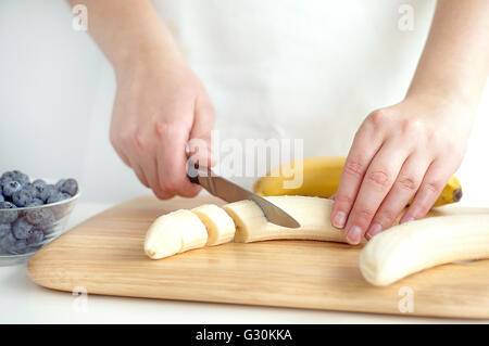 La donna a banana per affettare sul tagliere di legno Foto Stock