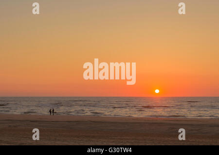 Un tramonto con un paio tenendo le mani sulla spiaggia di Katwijk aan Zee, South Holland, Paesi Bassi. Foto Stock
