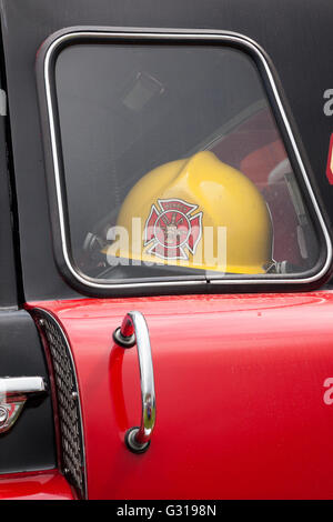 Primo piano di un vecchio Fire Engine d'epoca restaurato in mostra con l'elmetto dei vigili del fuoco mostrato all'interno. Inghilterra, Regno Unito Foto Stock