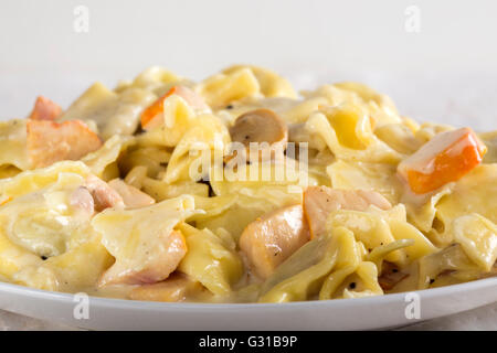 Tortellini e ravioli con panna acida, carne di pollo e funghi sulla piastra Foto Stock