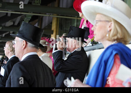 Ascot, Regno Unito, l'uomo con il cilindro guarda attraverso il suo binocolo Foto Stock