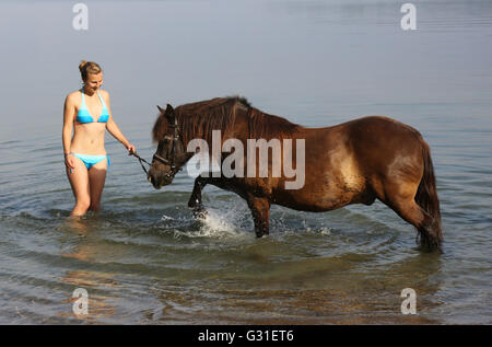 Schwerin, Germania, giovane donna sta con il suo pony nel lago Schwerin Foto Stock