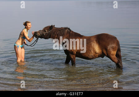 Schwerin, Germania, giovane donna sta con il suo pony nel lago Schwerin Foto Stock