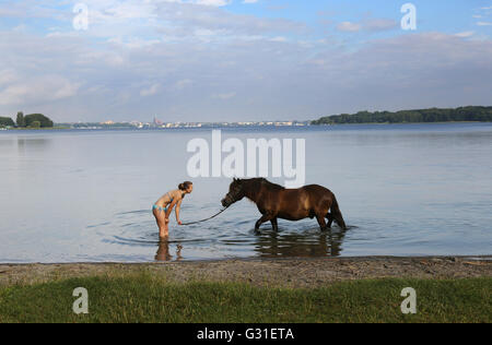 Schwerin, Germania, giovane donna sta con il suo pony nel lago Schwerin Foto Stock