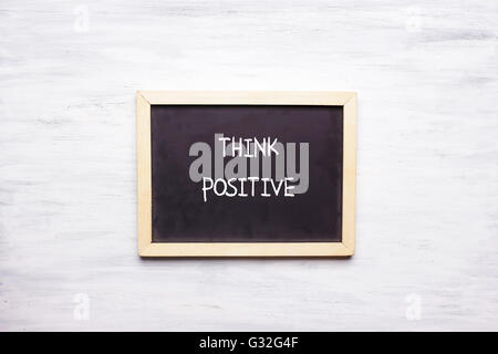 Vista superiore della lavagna con citazione pensare positivo scritto su di esso. La motivazione e il concetto di leadership. Foto Stock