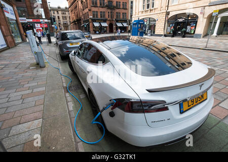 Tesla auto elettrica carica sulla strada nel quartiere mercantile della cittã di Glasgow, Regno Unito Foto Stock