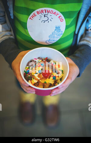 Ragazzo vasca di contenimento di frozen yogurt con un pizzico Foto Stock