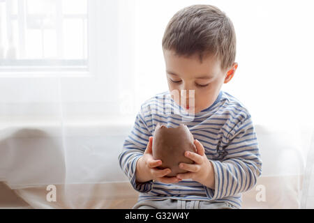 Ragazzo di mangiare una grande cioccolato uovo di pasqua Foto Stock