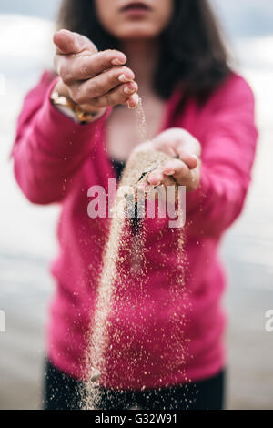 Donna con sabbia che corre attraverso le mani Foto Stock