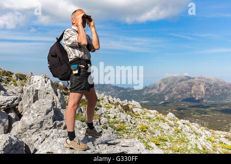 Uomo olandese sulla montagna rocciosa guardando attraverso il binocolo Foto Stock