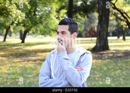 Ritratto di giovane uomo latino riflessivo in un parco. All'esterno. Foto Stock